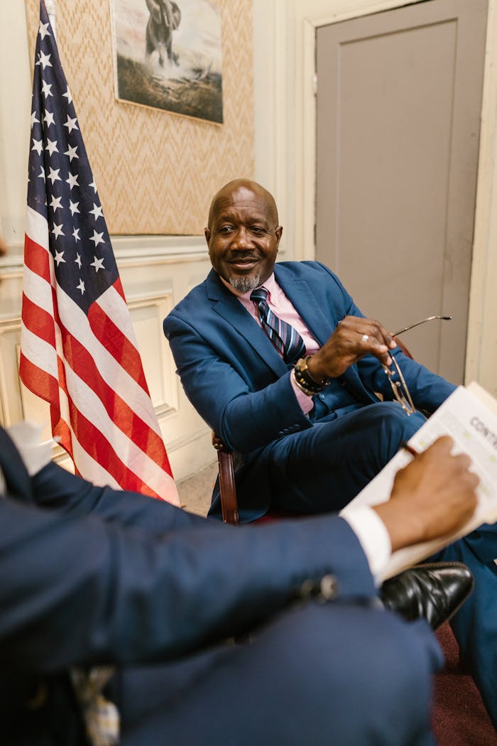 Man in Blue Suit Jacket Sitting Beside Man in Blue Suit